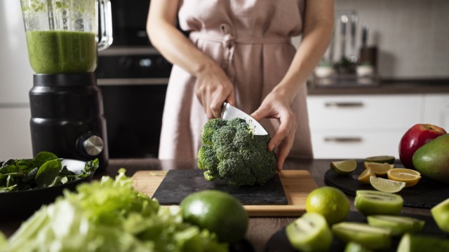 Persona preparando un plato colorido con vegetales frescos y crudos, representando la alimentación raw.