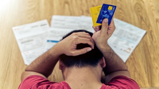 Hombre revisando estados de cuenta y calculadora, representando la consolidación de deudas.