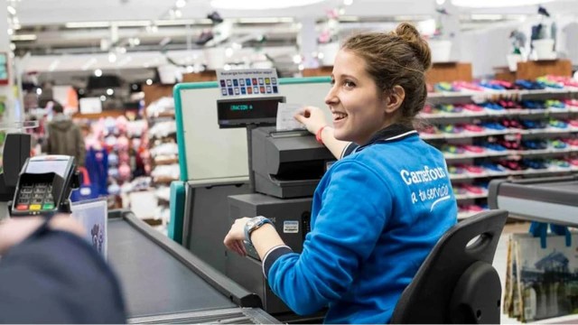 Cajero de supermercado procesando una compra en la línea de cajas