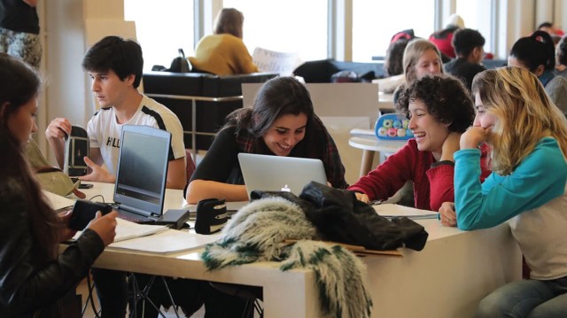 Estudiantes en aula tecnológica con pantallas y gráficos de IA, ciberseguridad y energías renovables