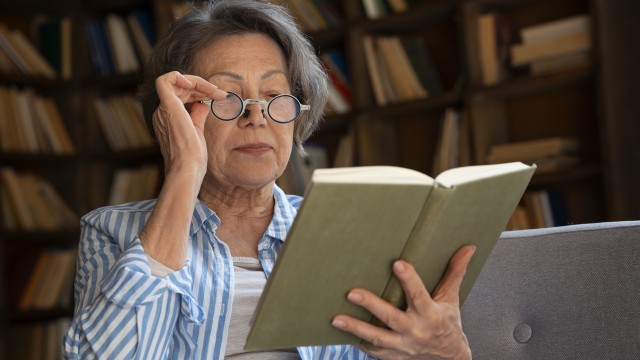 Persona mayor leyendo un libro en un ambiente tranquilo, ilustrando el hábito de la lectura.