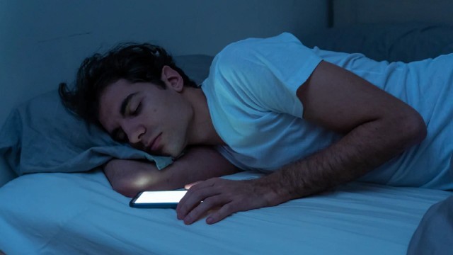 Persona cabeceando frente a una pantalla con una serie de streaming en un ambiente nocturno