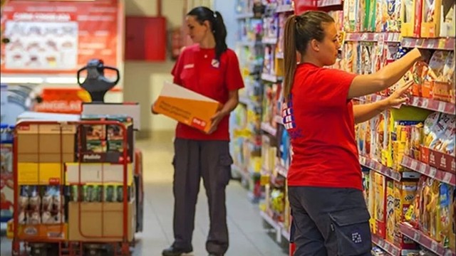 Repositor organizando productos en la góndola de un supermercado