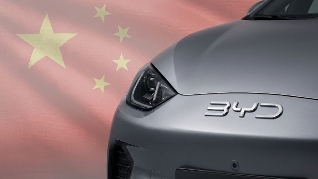 Autos en un concesionario con carteles de ofertas y modelos chinos de fondo
