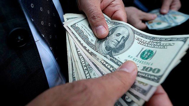 Persona contando billetes de dólar en una cueva financiera de la City porteña