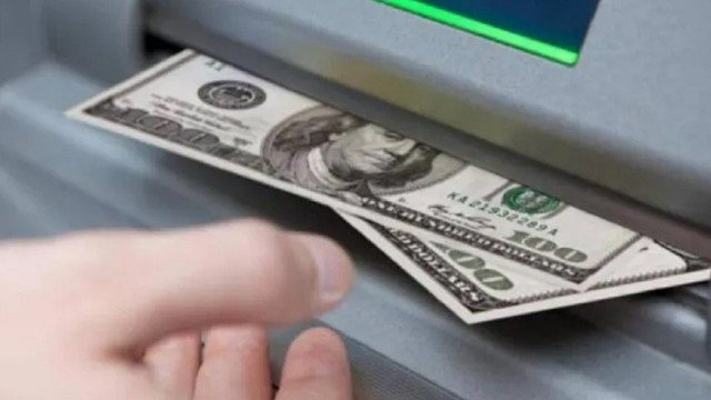Persona contando billetes de dólar sobre una mesa