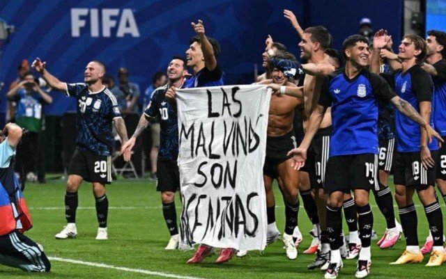 Jugadores de la Selección argentina despliegan una bandera blanca con la frase Las Malvinas son argentinas en el campo de juego del Mercedes-Benz Stadium