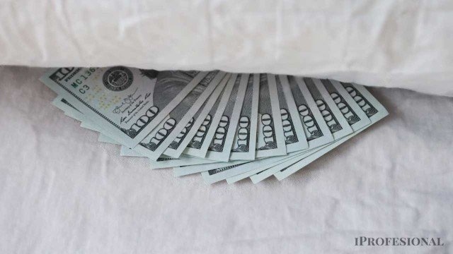 Fajo de billetes de dólar sobre una superficie oscura